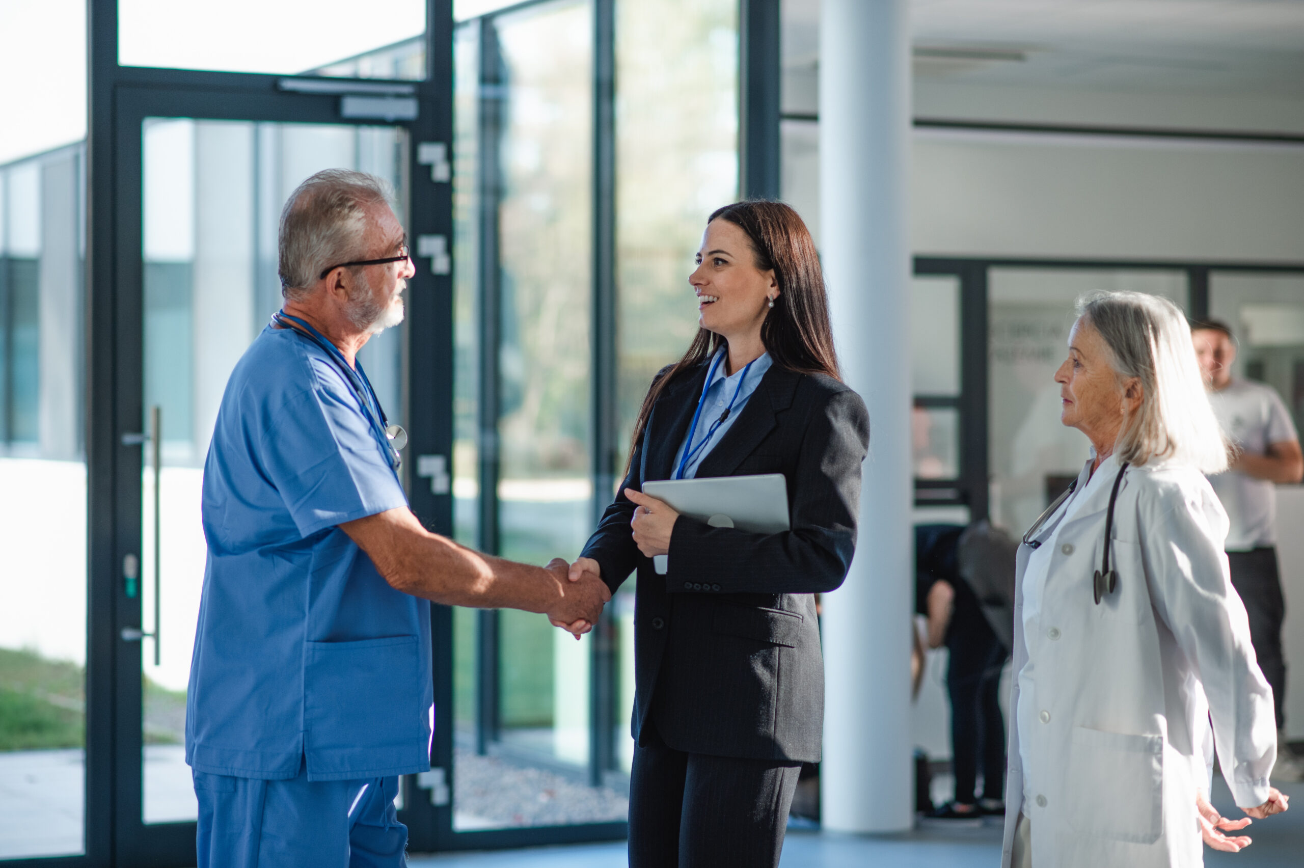 Young business woman shaking hand with elderly doctor.