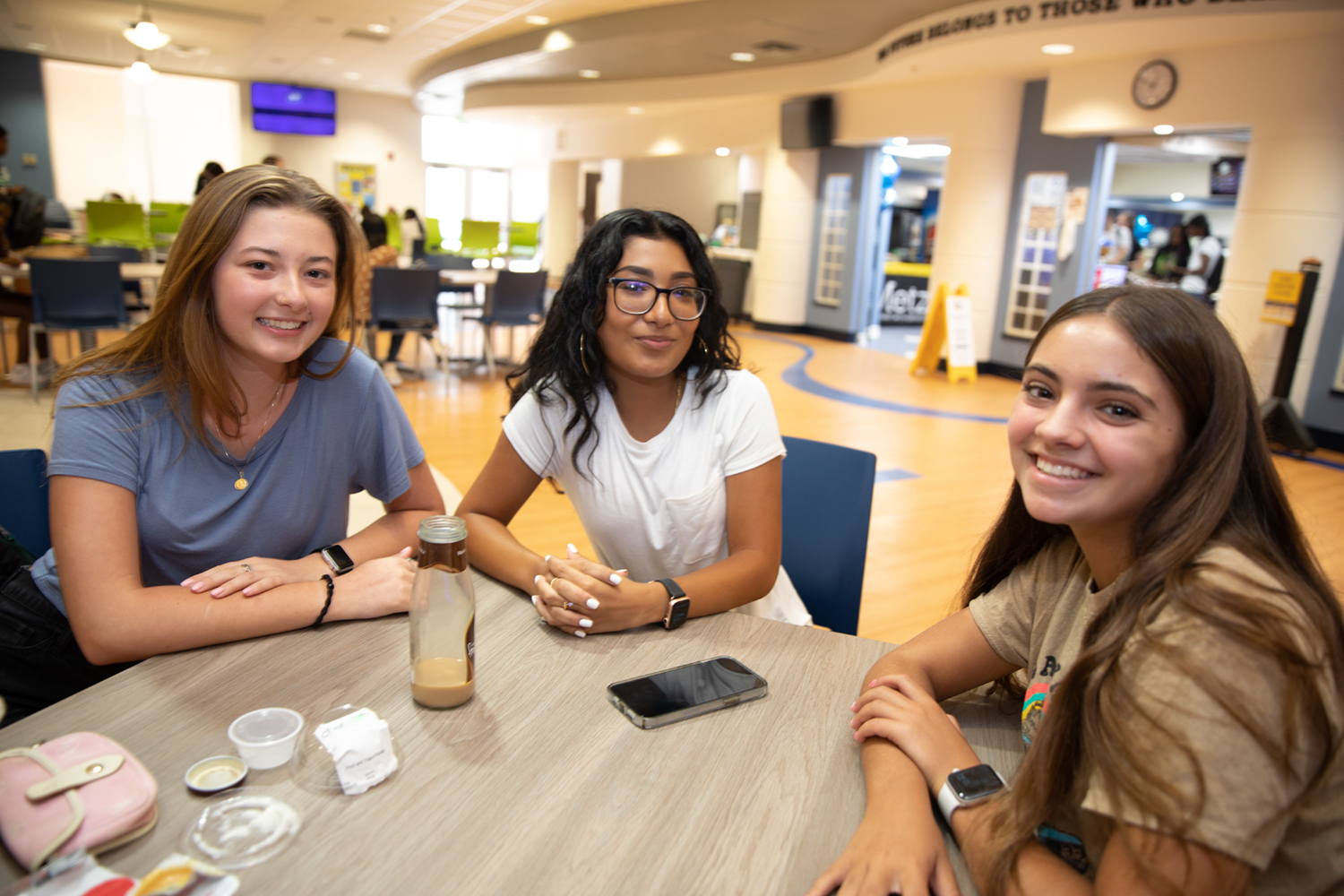 3 female students enjoy lunch in the cafeteria