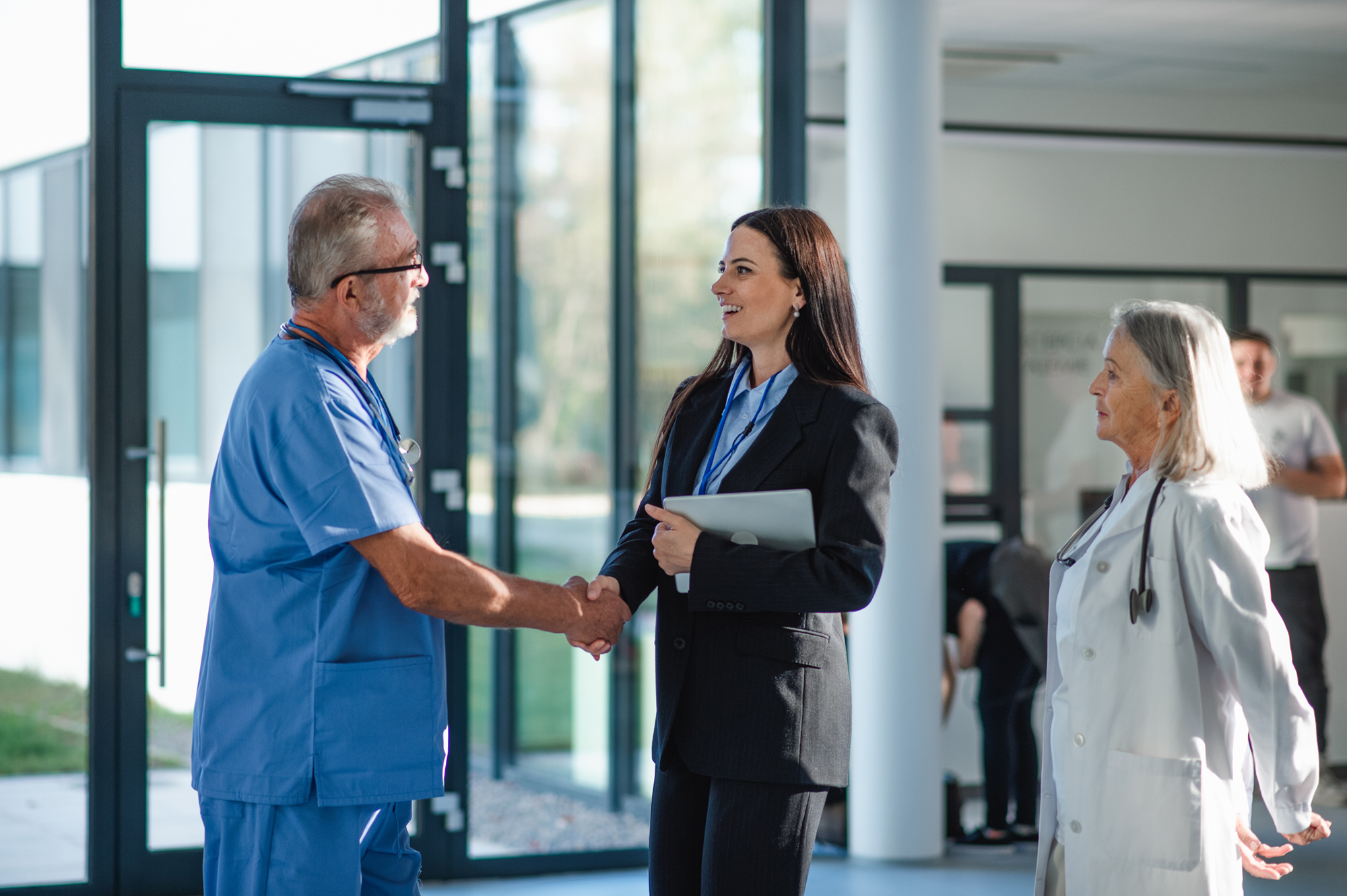 Young business woman shaking hand with elderly doctor.