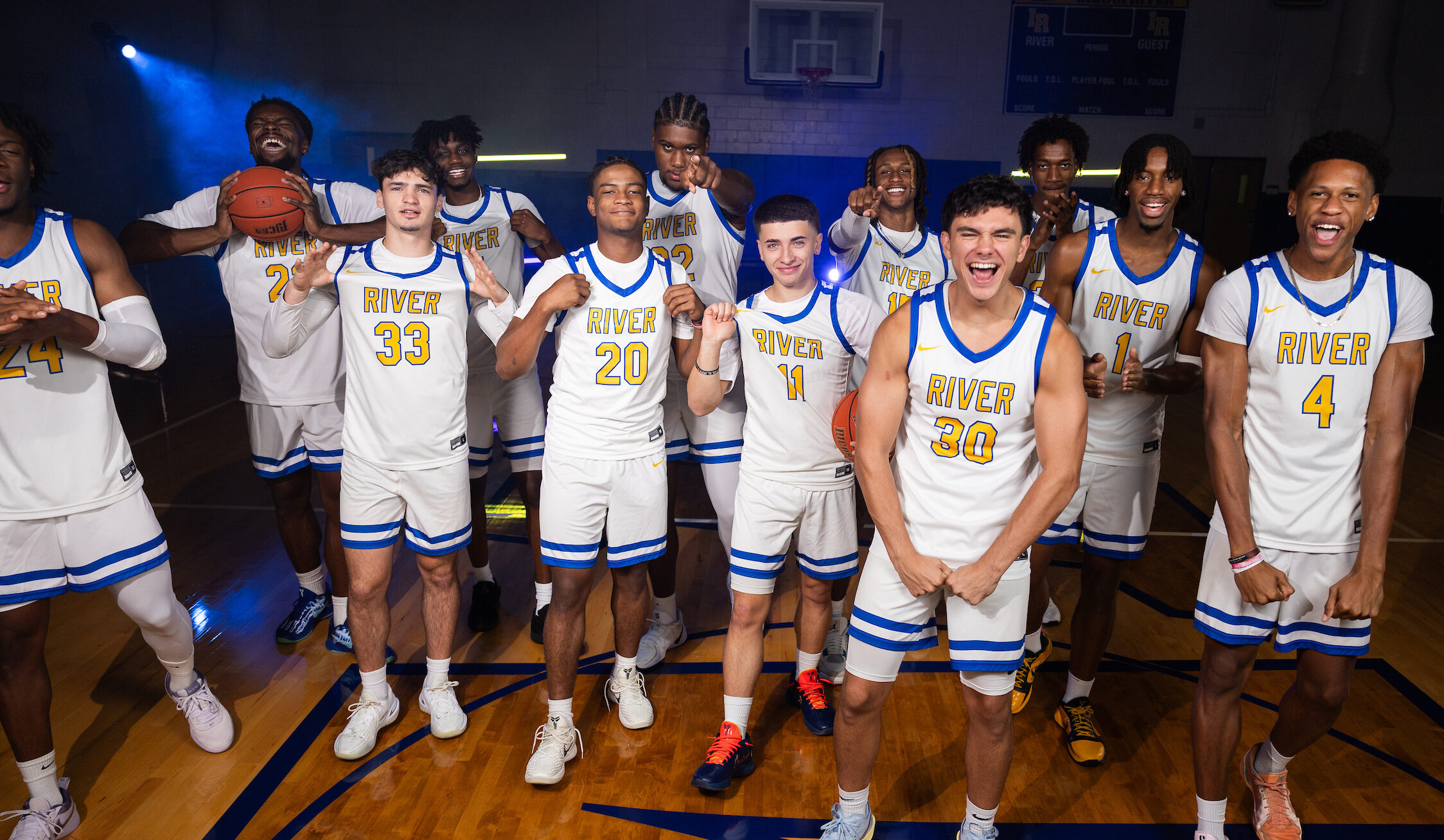Indian River State College Men’s Basketball players in white and blue uniforms pose together on the gym court, celebrating teamwork and excitement for the upcoming season.