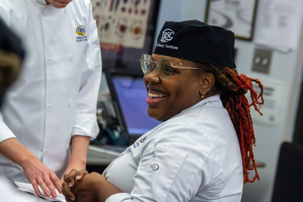 Female student smiling while working in a kitchen classroom at Indian River State College