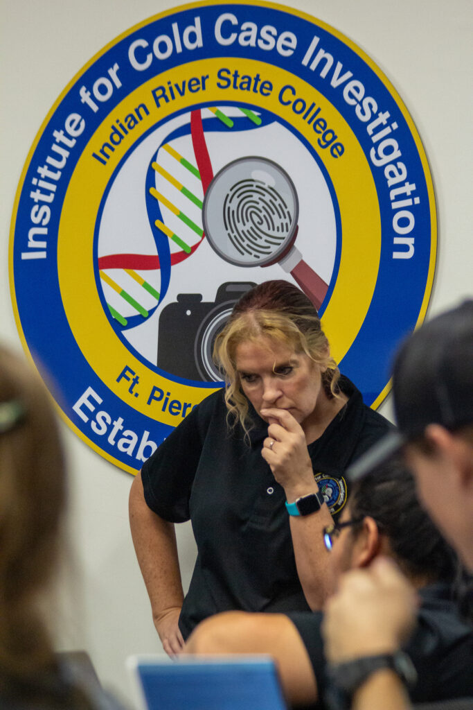 A photo of Dr. Kimberlie Massnick as she teaches with a sign of the Institute for Cold Case Investigation behind her.