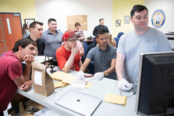 A photo of a group of students looking at a video monitor.
