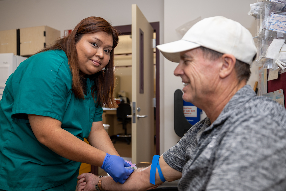 Phlebotomy technician drawing blood from a patient