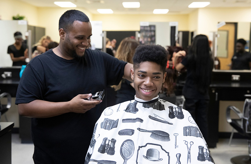 Barbering student practicing cuts with mannequin head